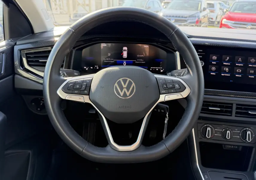 Vue intérieure centrée sur le volant multifonction cuir du Volkswagen Taigo avec tableau de bord digital et écran tactile.