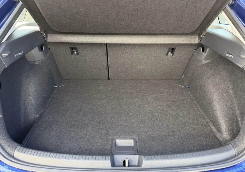 Coffre ouvert du Volkswagen Taigo bleu, vue arrière montrant l'espace de chargement et le plancher réglable.