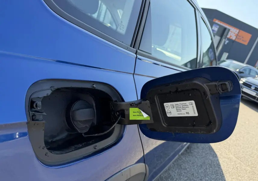 Vue rapprochée de la trappe à carburant ouverte côté gauche d’un Volkswagen Taigo bleu métallisé 2025.