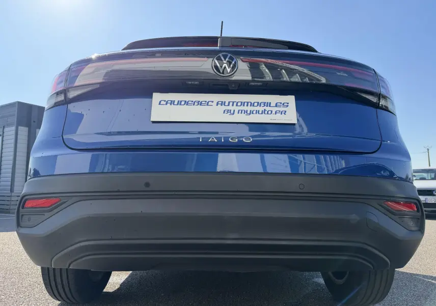 Vue arrière centrée d'un Volkswagen Taigo bleu métallisé avec feux arrière LED et caméra de recul visible.
