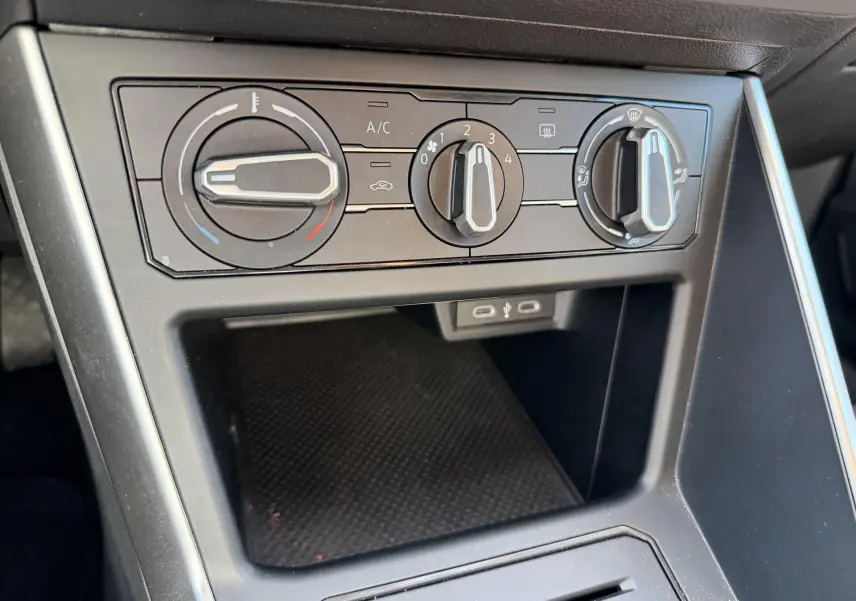 Vue rapprochée des commandes de climatisation manuelle et des ports USB-C dans l'habitacle du Volkswagen Taigo bleu 2025.