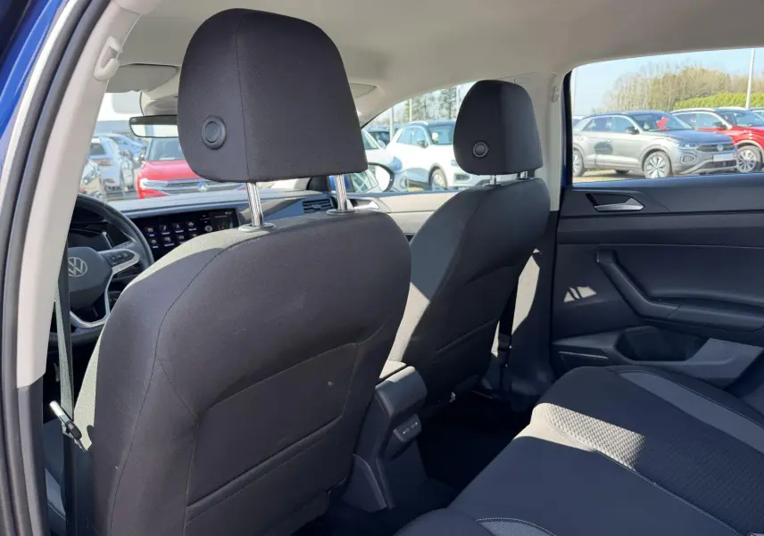 Vue intérieure arrière du Volkswagen Taigo 2025, sièges tissu noirs et console centrale avec ports USB visibles.