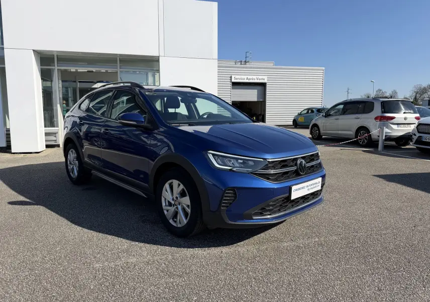 Volkswagen Taigo bleu métallisé en vue 3/4 avant droit, avec jantes alliage et calandre noire brillante.