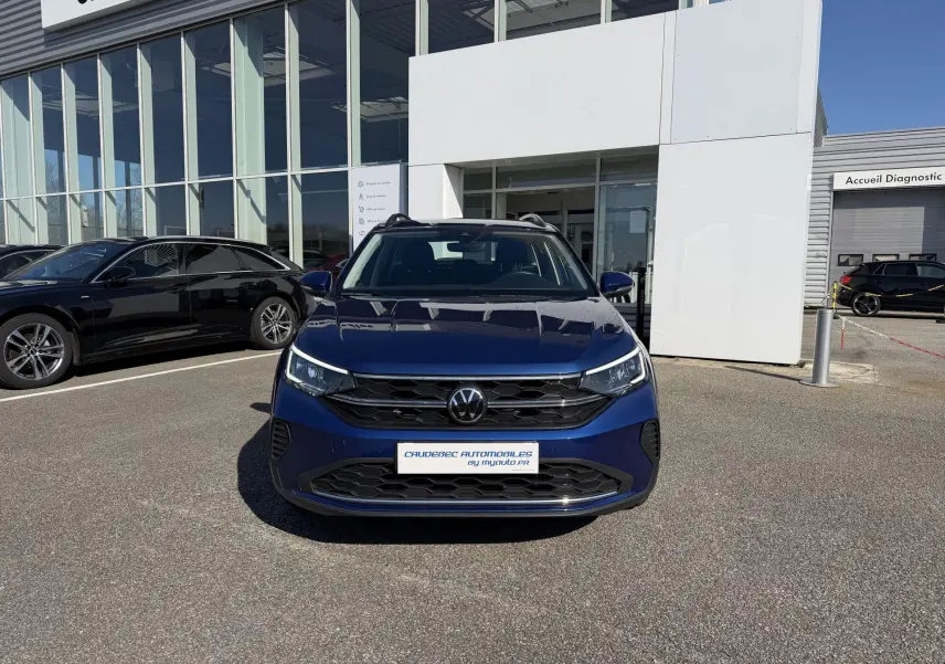 Volkswagen Taigo bleu métallisé vue de face, avec calandre noire et phares LED allumés.