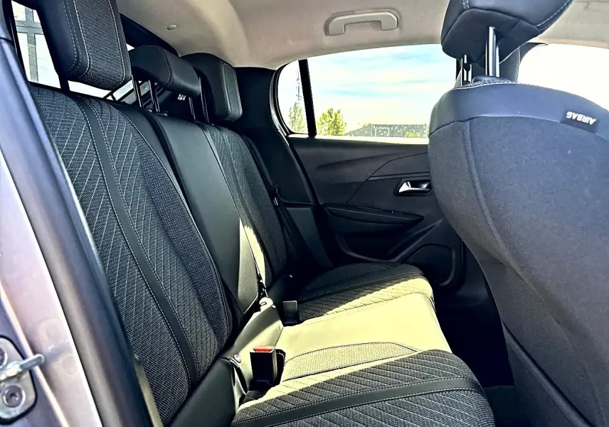 Vue intérieure côté gauche des sièges arrière en tissu gris foncé de la Peugeot 208 1.2 100 Allure 2025.