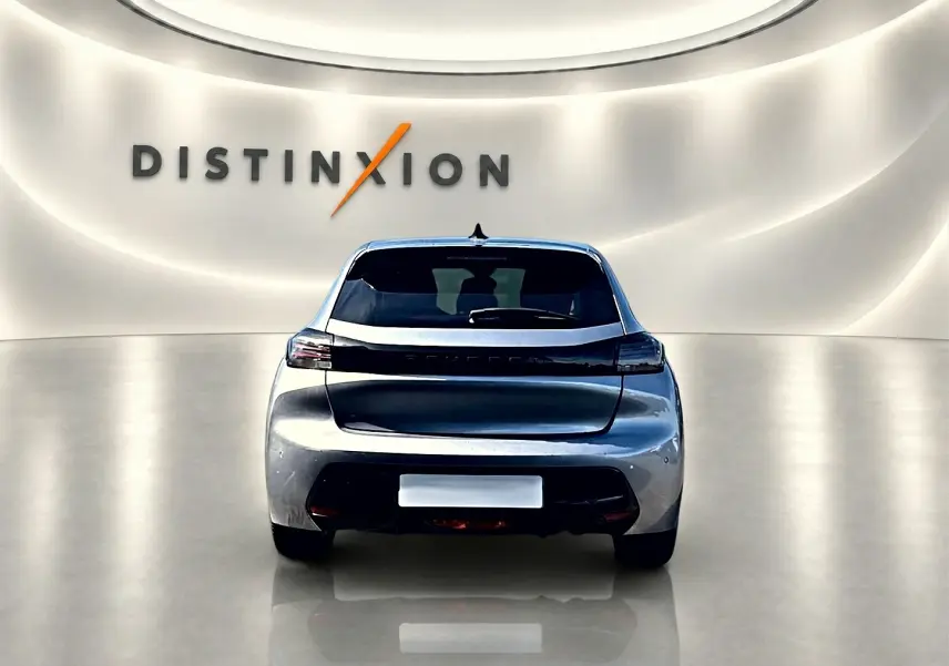 Vue arrière d'une Peugeot 208 1.2 100 Allure gris Artense dans un showroom lumineux avec logo Distinxion en arrière-plan.