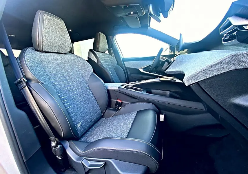 Vue intérieure côté passager avant du Peugeot 5008 Hybrid 145 allure e-dcs6 2025 avec sièges tissu bleu et cuir noir.