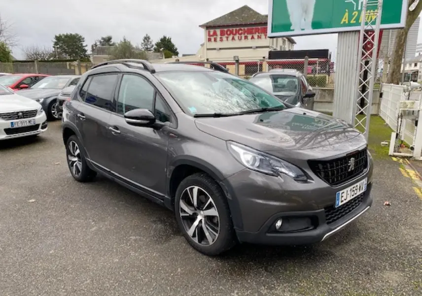 Peugeot 2008 gris foncé vue 3/4 avant droit avec jantes alliage 17 pouces et barres de toit noir brillant.