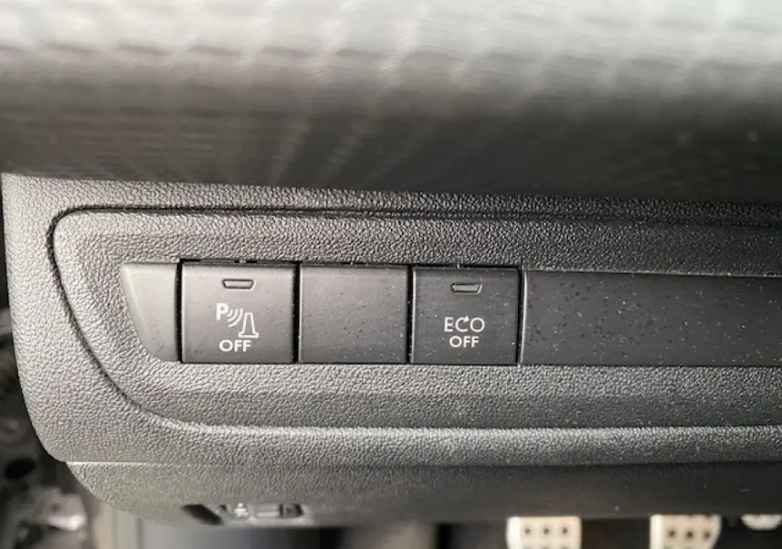 Gros plan sur les boutons de commande du tableau de bord du Peugeot 2008 gris foncé, avec fonction parking et mode ECO désactivés.