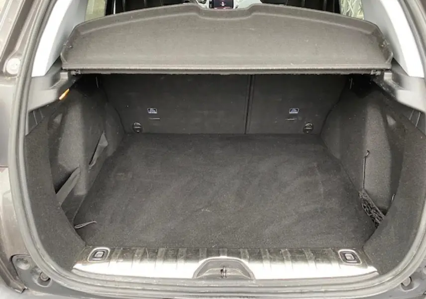 Coffre ouvert d'un Peugeot 2008 gris foncé, vue arrière montrant l'espace de chargement vide et la plage arrière relevée.