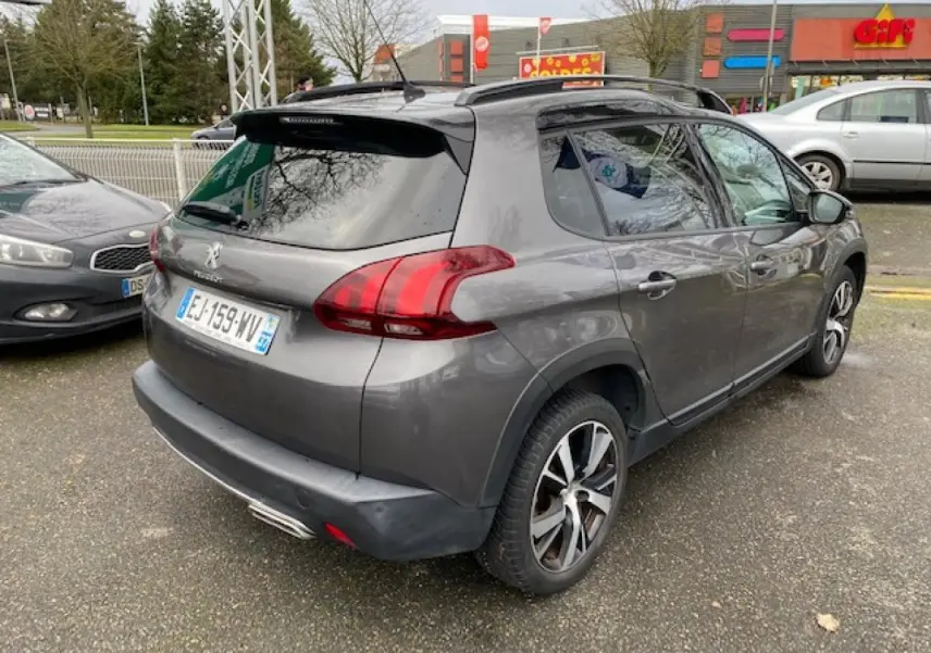Peugeot 2008 gris foncé vue 3/4 arrière droit avec jantes alliage 17 pouces et barres de toit noir brillant.