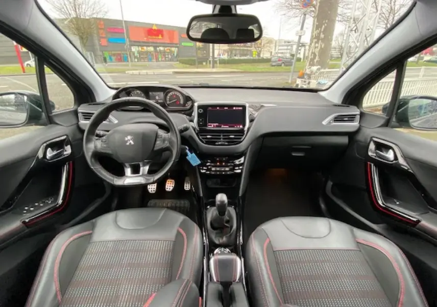 Intérieur Peugeot 2008 GT Line 2017 vu de face, sièges noirs avec surpiqûres rouges et volant compact sport.