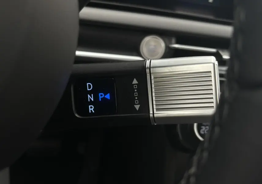 Gros plan sur la commande de boîte automatique avec sélecteur digital et finition métallique dans un Hyundai Tucson blanc.