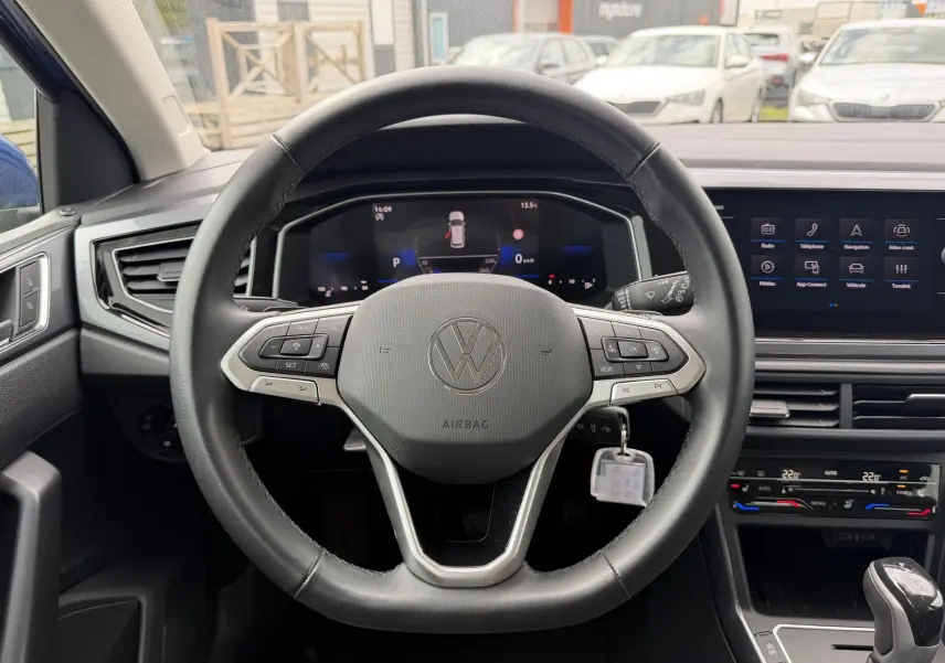 Vue intérieure centrée sur le volant cuir multifonctions d'une Volkswagen Polo 2025 avec tableau de bord digital et écran tactile.