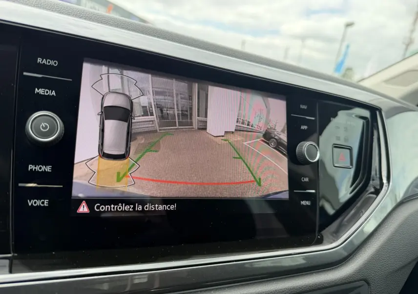 Écran tactile de la caméra de recul dans l'habitacle d'une Volkswagen Polo bleue, vue intérieure côté conducteur.