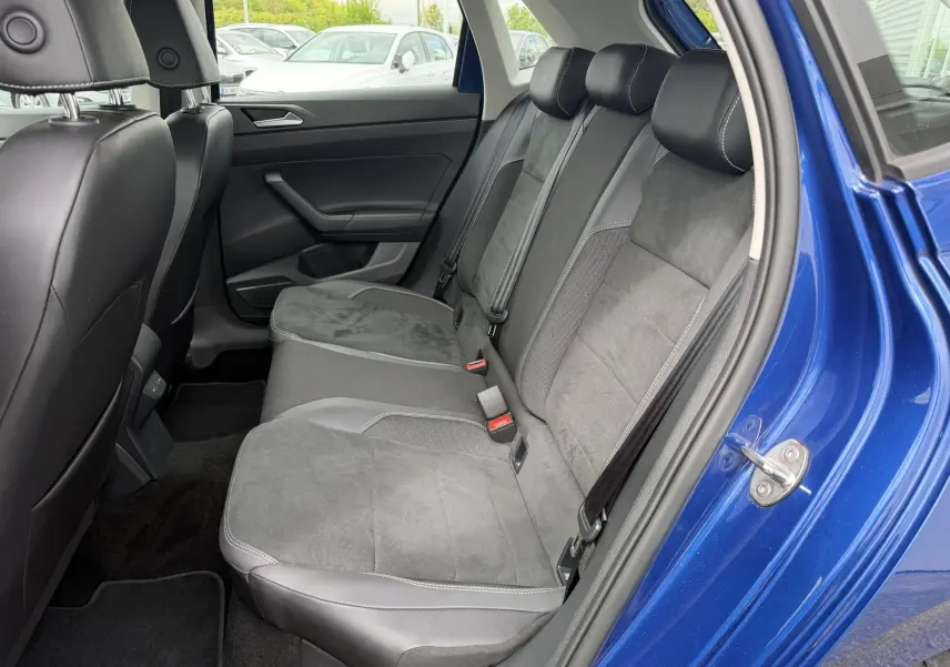 Vue latérale droite de l'intérieur arrière d'une Volkswagen Polo bleue avec sièges sport en cuir et alcantara noirs.