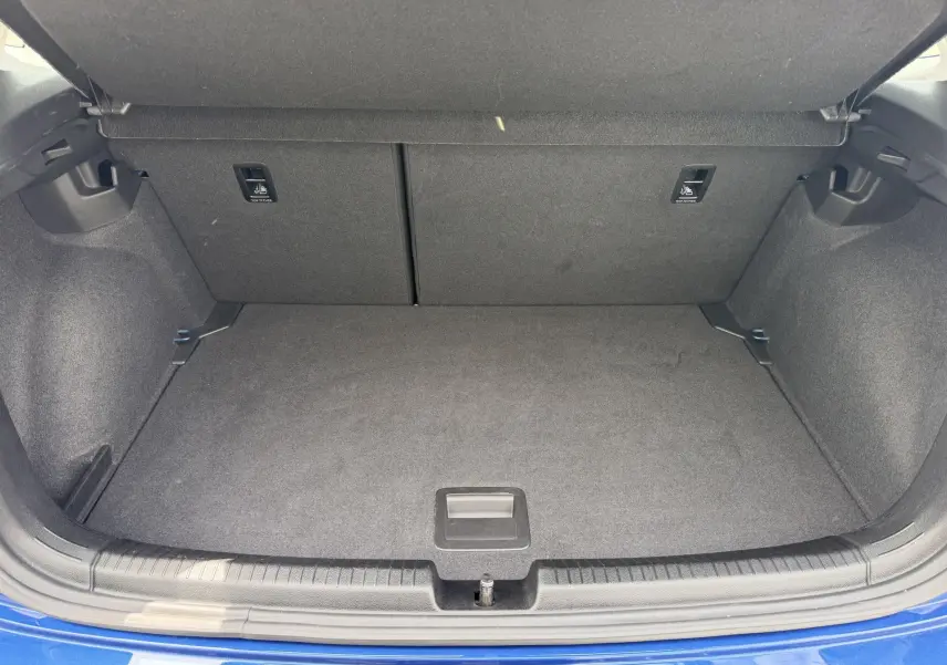 Coffre ouvert vu de l'arrière d'une Volkswagen Polo bleue 2025, montrant un espace de rangement propre et vide.