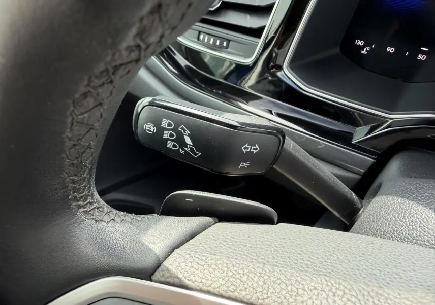 Gros plan sur le commodo de clignotant noir à gauche du volant cuir dans l’habitacle de la Volkswagen Polo bleue 2025.