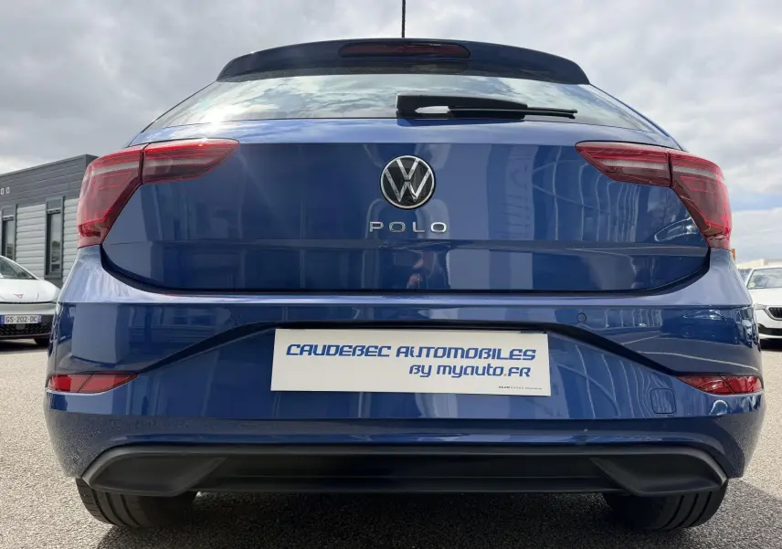 Vue arrière d'une Volkswagen Polo bleue 2025 avec feux LED et logo central sur un parking extérieur.