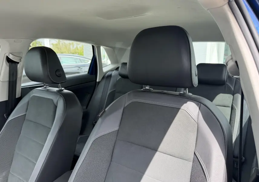 Vue intérieure rapprochée des sièges avant et arrière en tissu noir et gris d'une Volkswagen Polo bleue.