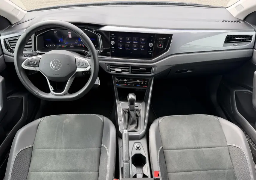 Vue intérieure avant de la Volkswagen Polo 2025, tableau de bord noir avec écran tactile et volant cuir multifonctions.