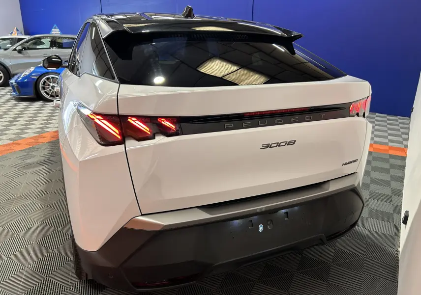 Vue 3/4 arrière droite du Peugeot 3008 blanc Okenite avec feux arrière LED allumés et toit noir brillant.