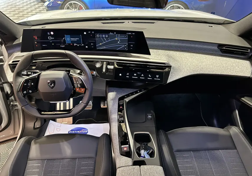Vue intérieure du poste de conduite du Peugeot 3008 blanc Okenite, avec tableau de bord numérique et volant multifonction.