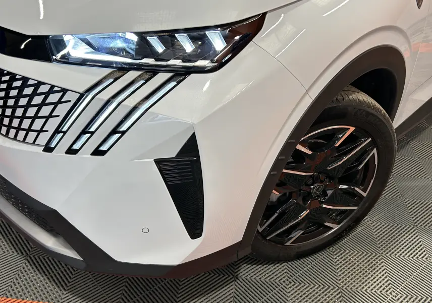 Gros plan sur l'avant droit blanc Okenite du Peugeot 3008 Hybrid avec phares LED et jante noire brillante.