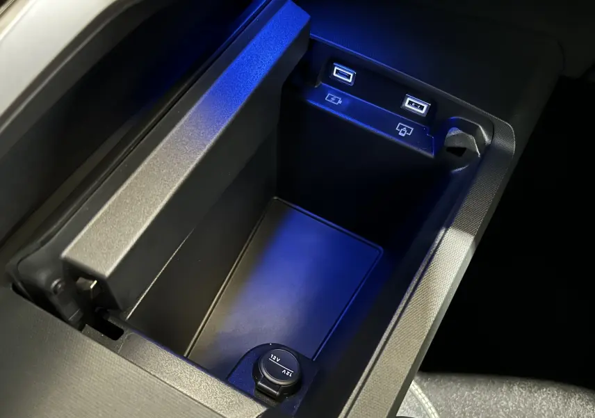Vue rapprochée de la console centrale noire du Peugeot 3008 Hybrid avec ports USB et prise 12V éclairés en bleu.