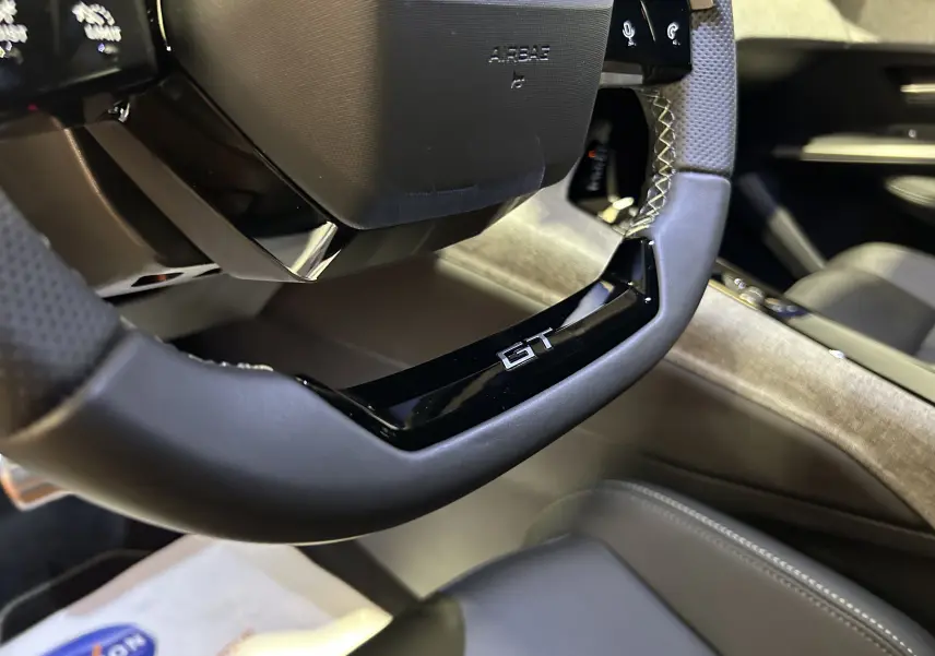 Gros plan sur le volant GT noir avec surpiqûres, intérieur cuir gris du Peugeot 3008 Hybrid 2025.
