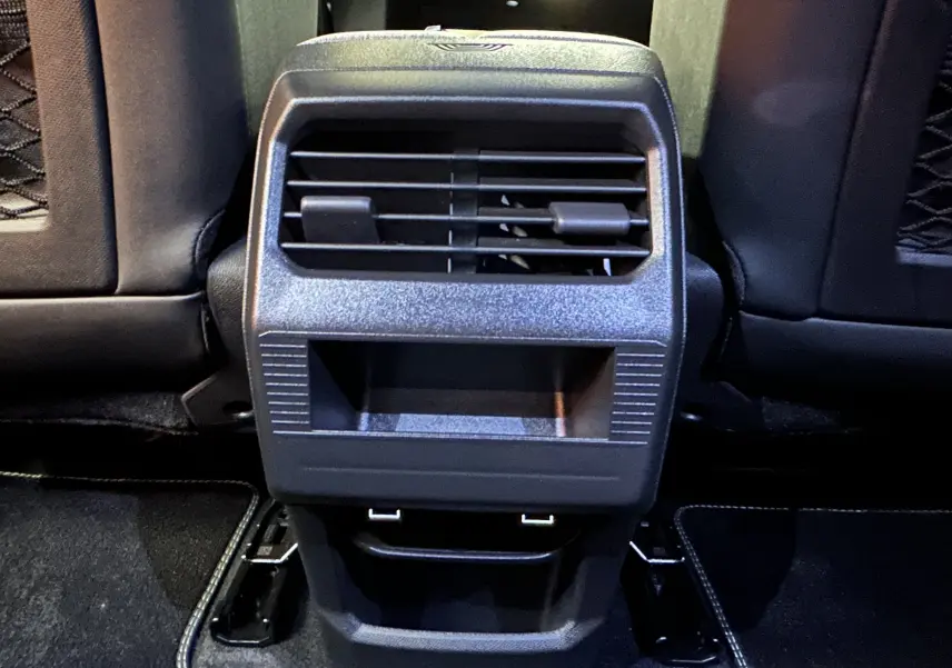 Vue rapprochée de la console arrière noire avec bouches d’aération et ports USB du Peugeot 3008 Hybrid blanc Okenite.