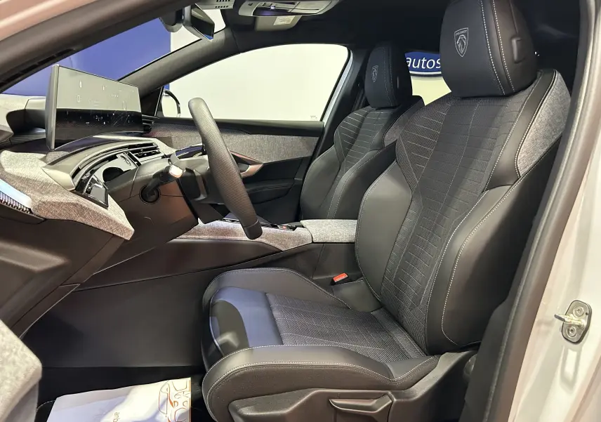 Vue intérieure côté conducteur du Peugeot 3008 Hybrid blanc, sièges noirs avec logo Peugeot brodé et tableau de bord moderne.