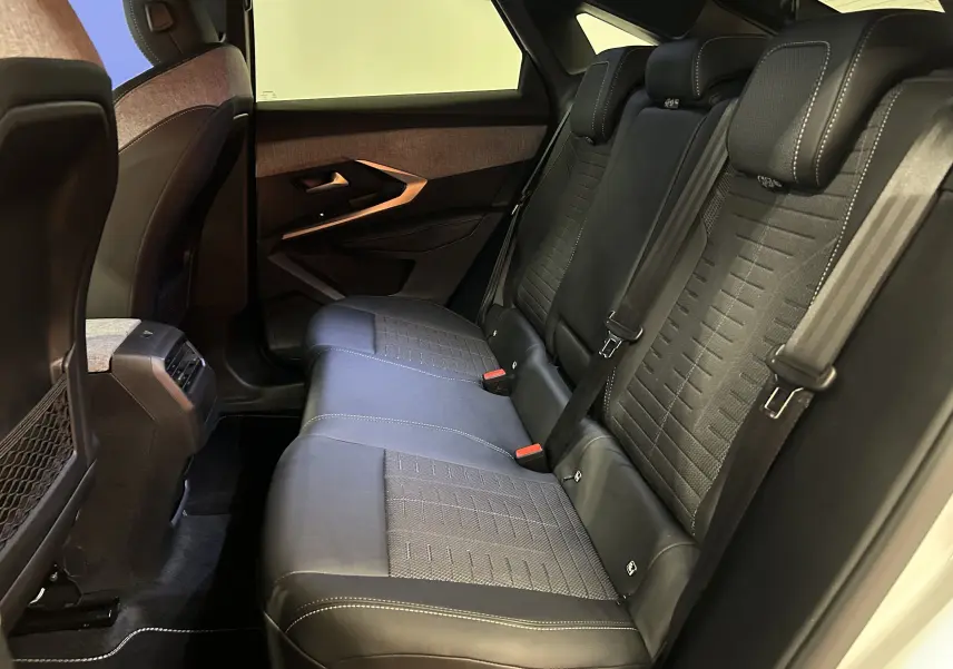 Vue intérieure côté droit des sièges arrière en cuir noir avec surpiqûres blanches et garnitures tissu du Peugeot 3008 Hybrid 2025.