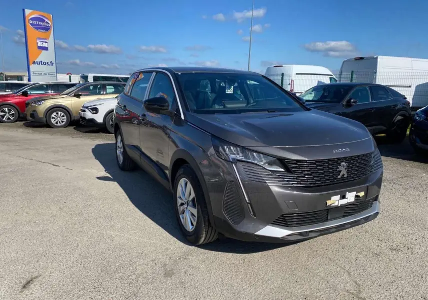 Peugeot 5008 gris platinium métal vue 3/4 avant droit sur parking avec calandre noire et phares LED.