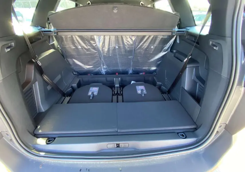 Coffre ouvert du Peugeot 5008 gris platinium, montrant les sièges arrière rabattus et la plage arrière déployée.
