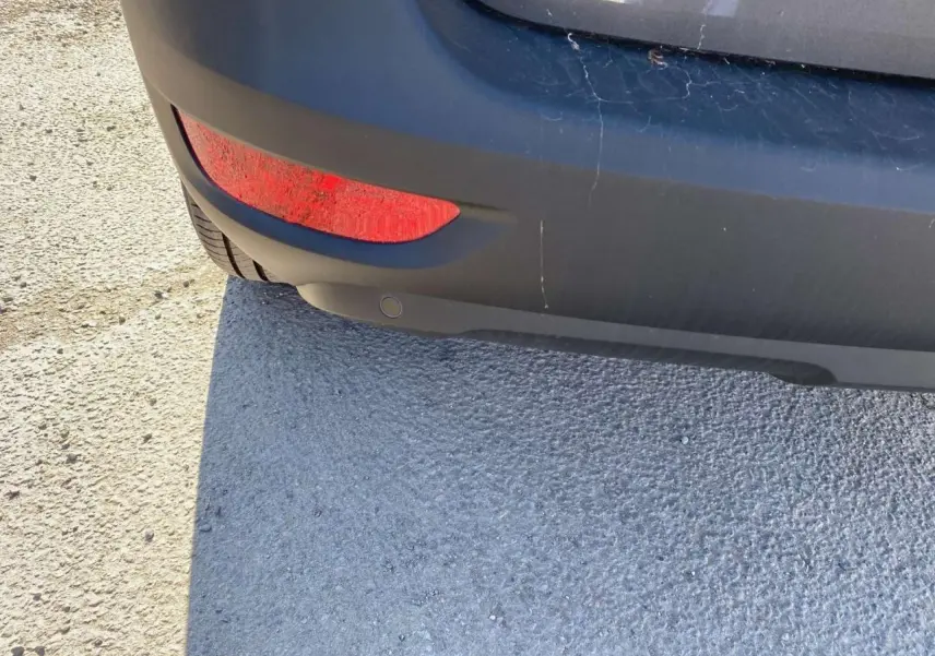 Gros plan sur le pare-chocs arrière gris platinium métallisé d'un Peugeot 5008 2023 avec feu rouge et capteur de stationnement.