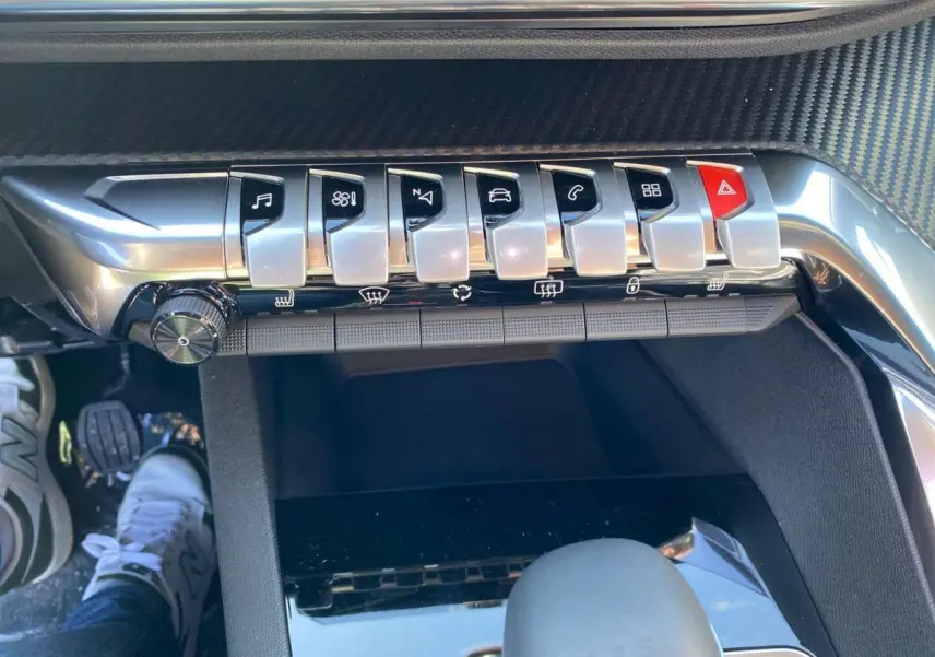 Gros plan sur la console centrale du Peugeot 5008 2023, montrant les touches piano chromées et le levier de vitesse.