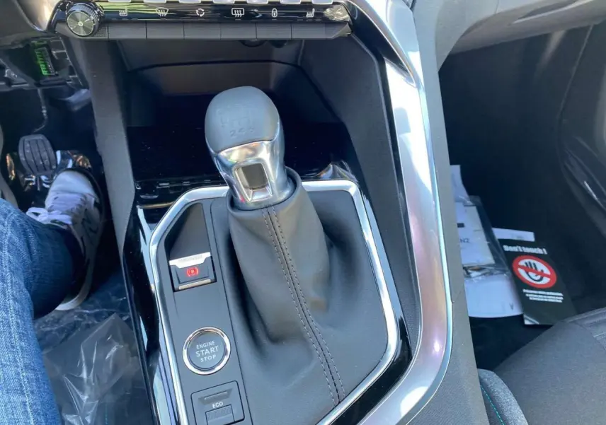Gros plan sur la console centrale du Peugeot 5008 gris platinium, mettant en valeur le levier de vitesse manuel et le bouton start/stop.