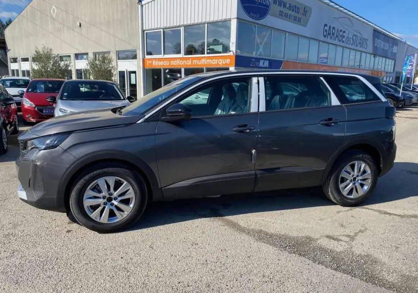 Profil côté gauche d'un Peugeot 5008 gris platinium métallisé, avec jantes alliage 17 pouces, stationné en extérieur.