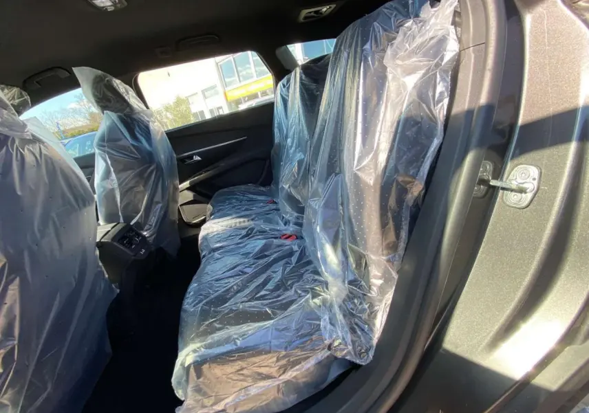 Vue côté gauche arrière du Peugeot 5008 gris platinium métal, sièges arrière protégés par housses plastiques.