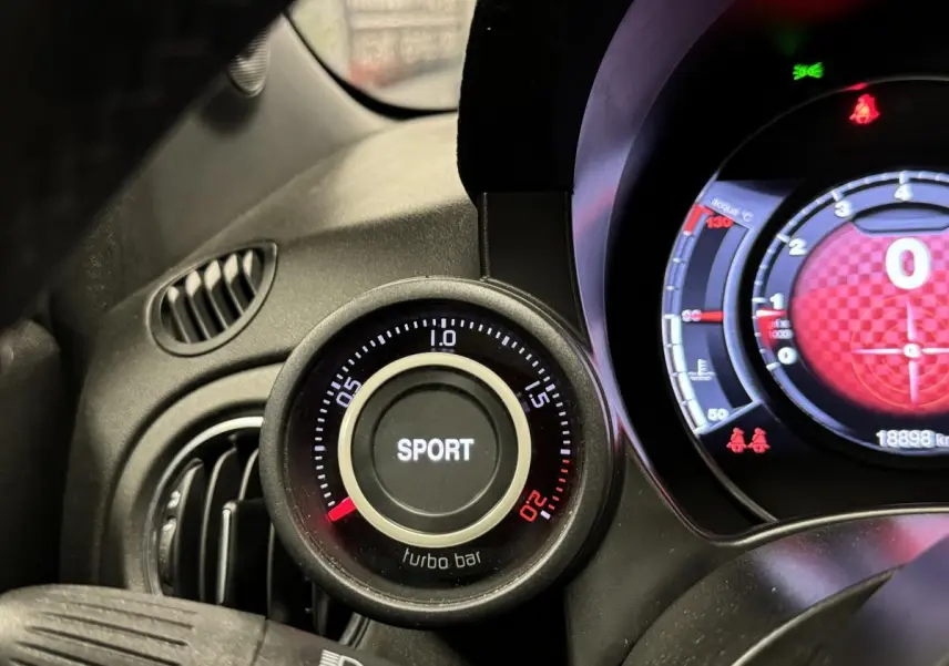 Gros plan sur le manomètre turbo avec mode Sport de l'Abarth 595 Competizione noir, tableau de bord partiellement visible.
