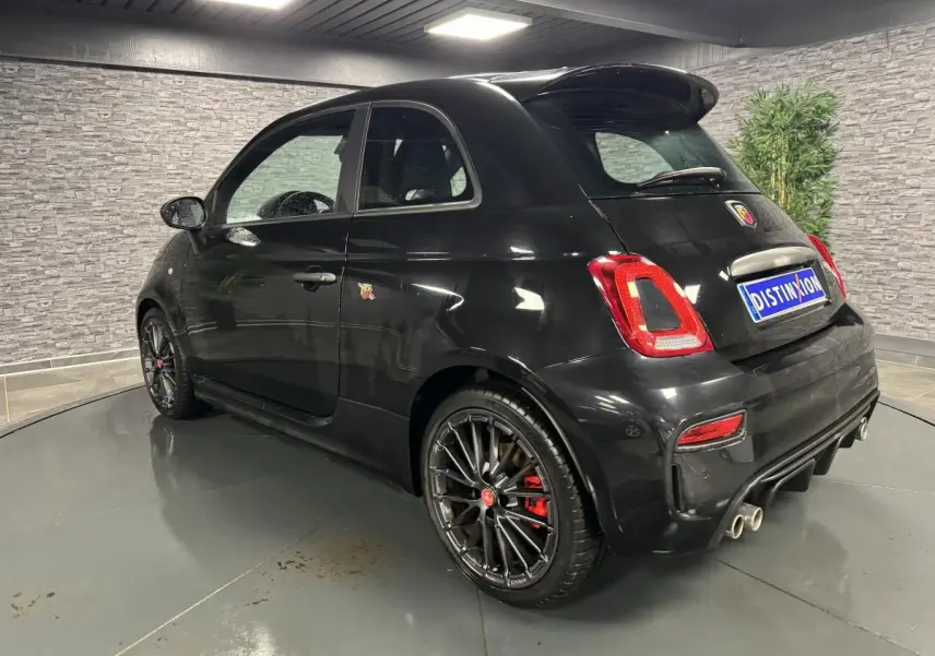 Vue 3/4 arrière droite de l'Abarth 595 Competizione noire avec jantes noires et échappement quadruple chromé.