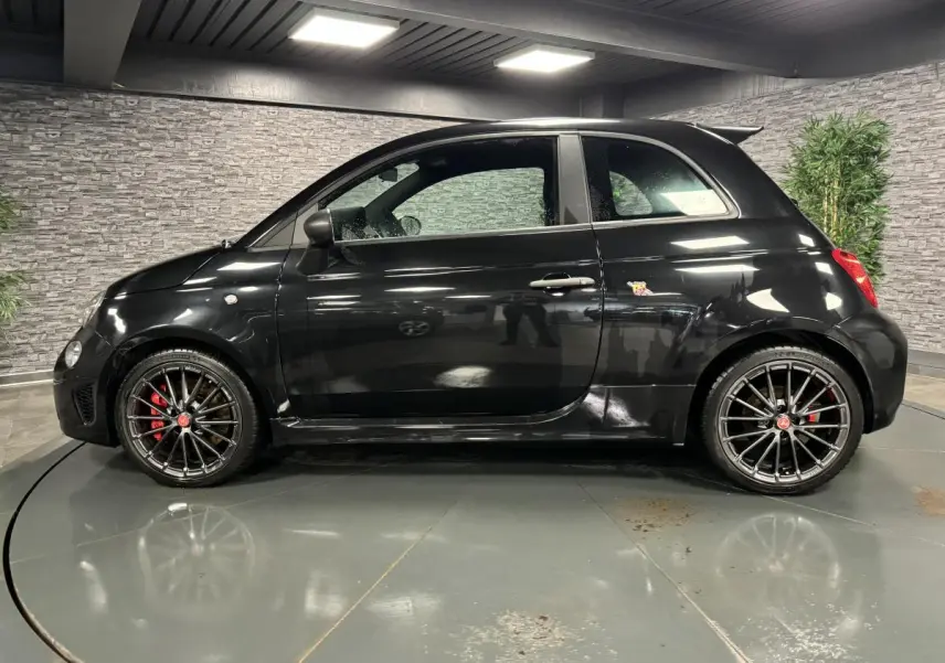 Profil côté gauche de l'Abarth 595 Competizione noire avec jantes alliage 17 pouces et étriers de frein rouges visibles.