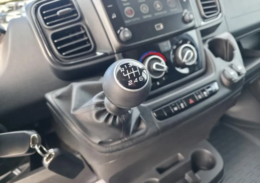 Gros plan sur le levier de vitesses manuel du Fiat Ducato Fourgon blanc, avec tableau de bord et commandes visibles.