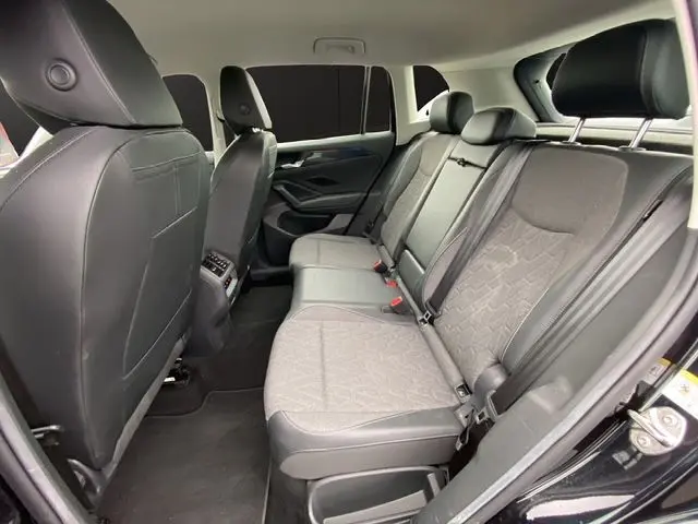 Vue intérieure arrière côté droit du Volkswagen Tiguan noir 2024, sièges tissu gris foncé et ceintures de sécurité visibles.