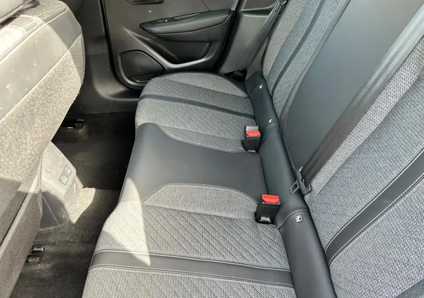 Vue intérieure côté droit des sièges arrière gris avec surpiqûres et ceintures de sécurité rouges d'une Peugeot 208 Hybrid 2024.