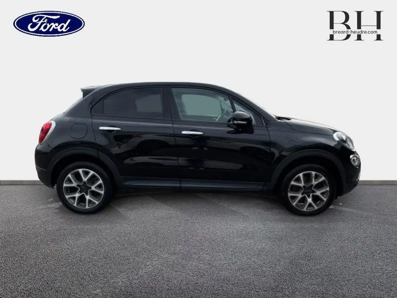 Vue de profil côté gauche d'une FIAT 500X noire Cinéma pastel avec jantes alliage et vitres surteintées.