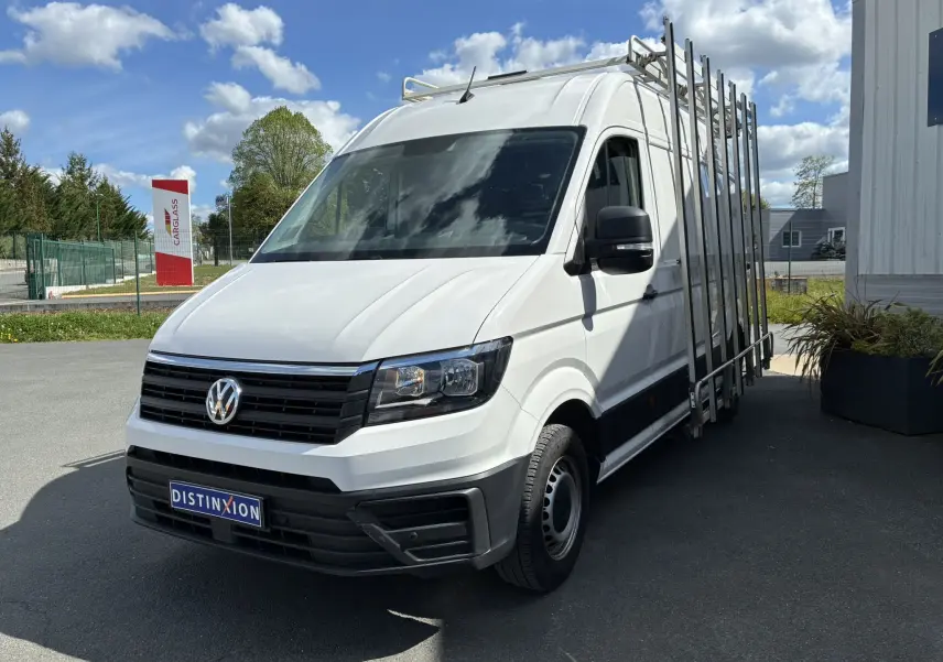 Volkswagen Crafter blanc vu en 3/4 avant droit avec porte-échelles latéral et calandre noire.