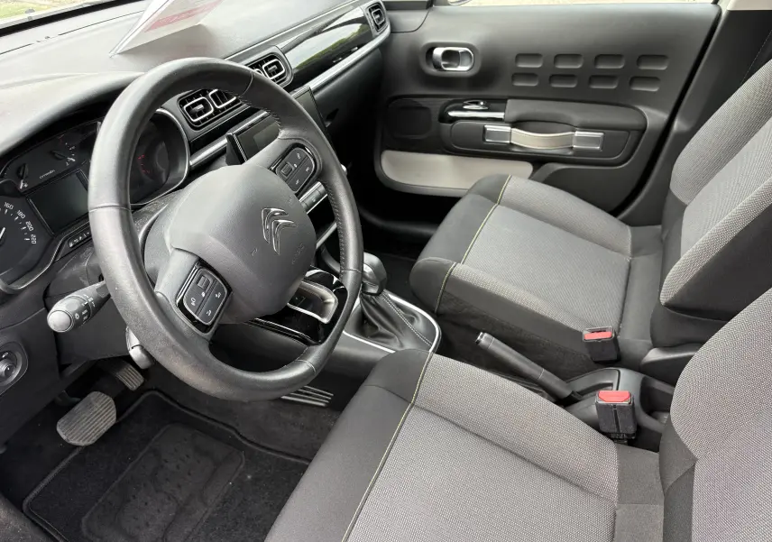 Intérieur beige de Citroën C3 2019 vu côté conducteur, volant multifonction et sièges tissu gris avec surpiqûres jaunes.