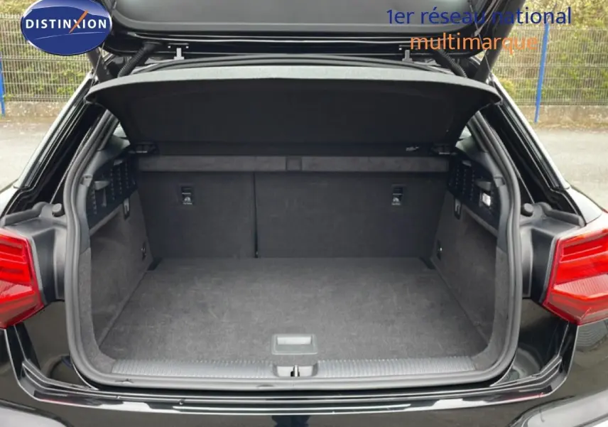 Coffre ouvert vu de l'arrière d'un Audi Q2 noir mito metal, avec banquette arrière rabattue et intérieur spacieux.